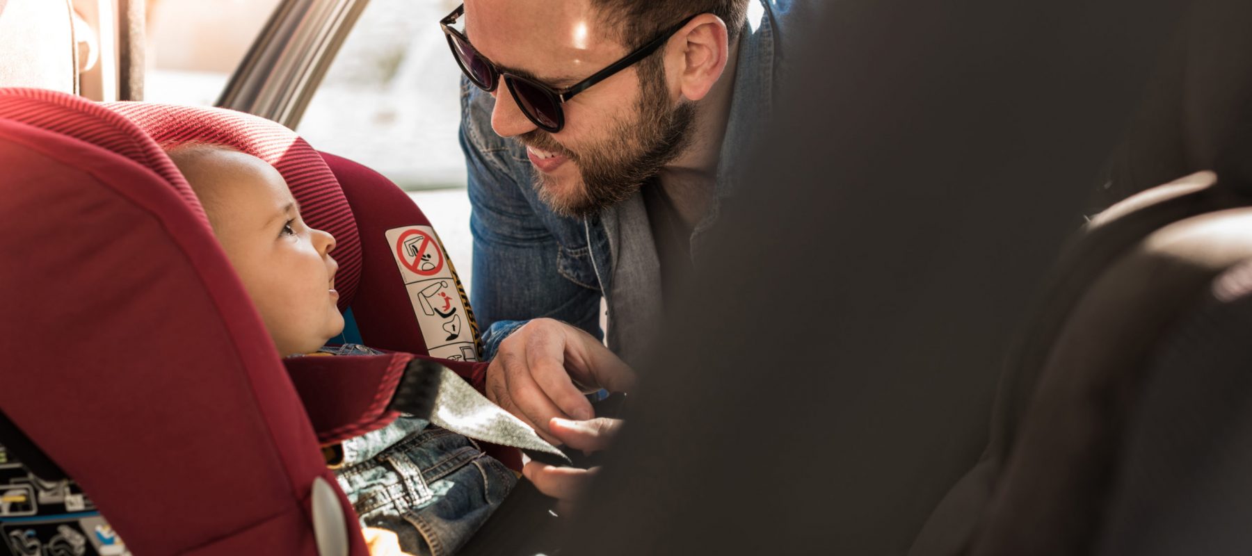 Father fasten his little baby in the car seat