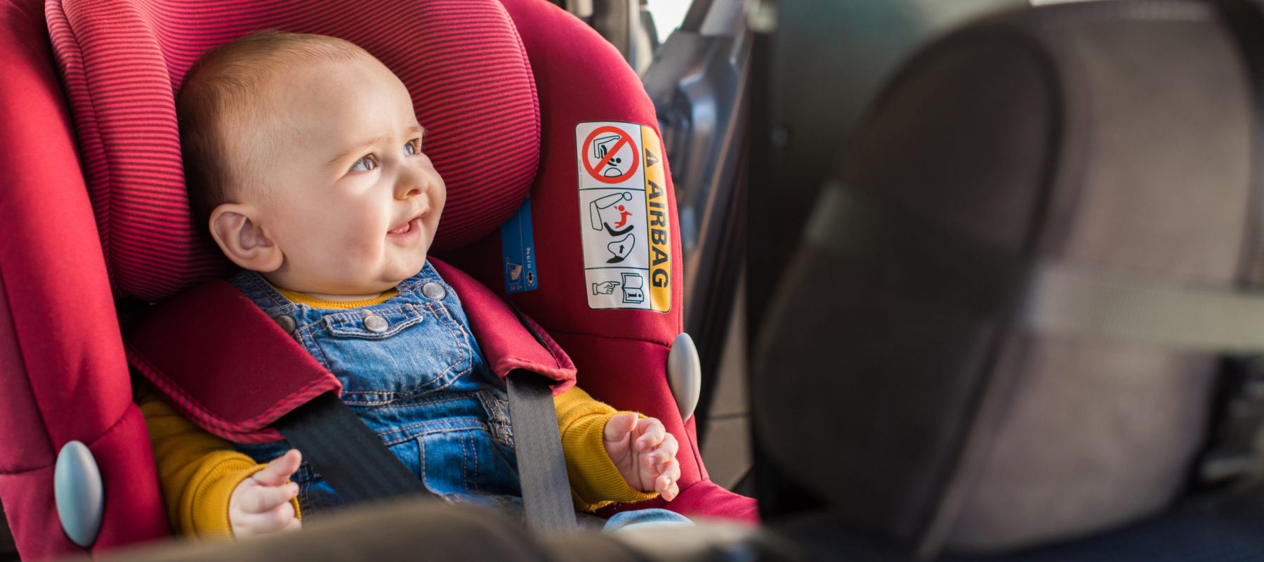 Father fasten his little baby in the car seat